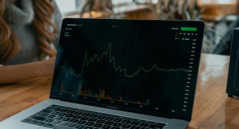 A laptop on a desk showing a green sales trend line