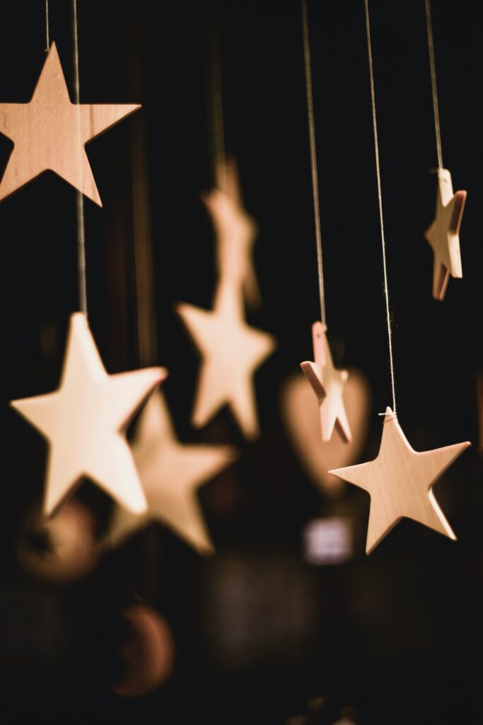 Hanging wooden stars on strings in a dark setting. Soft focus with warm lighting creates a calming, dreamy atmosphere.