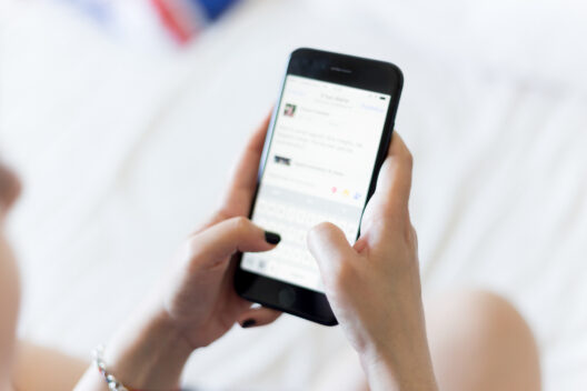 Person texting on smartphone in a white room