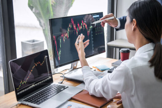 Business colleagues analyzing stock market data on computer screens